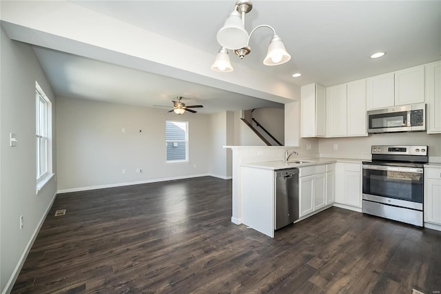 kitchen with light countertops, appliances with stainless steel finishes, dark wood-type flooring, a sink, and baseboards