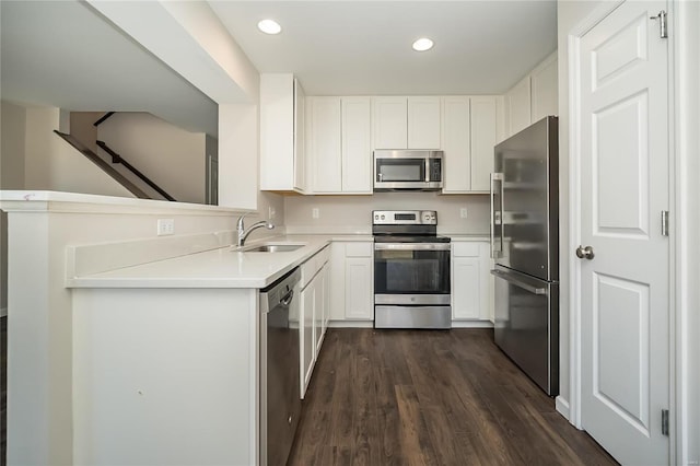 kitchen with dark wood-style floors, light countertops, appliances with stainless steel finishes, white cabinets, and a sink