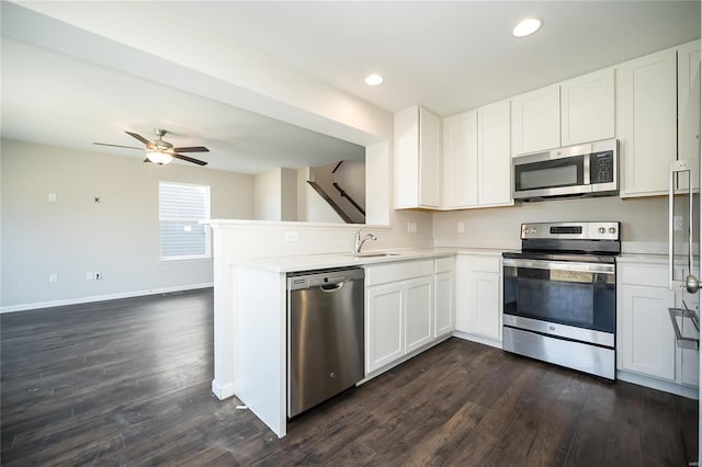 kitchen with white cabinets, appliances with stainless steel finishes, light countertops, and dark wood-style flooring