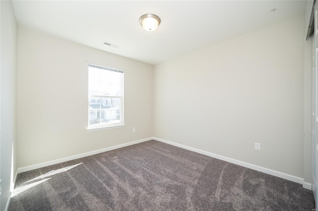 empty room featuring dark colored carpet, visible vents, and baseboards