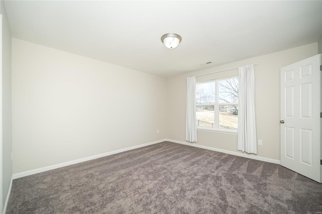 empty room featuring visible vents, baseboards, and dark colored carpet