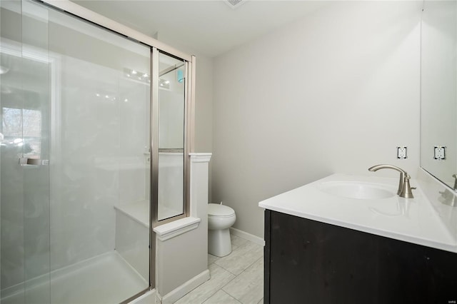 bathroom featuring a stall shower, vanity, toilet, and baseboards