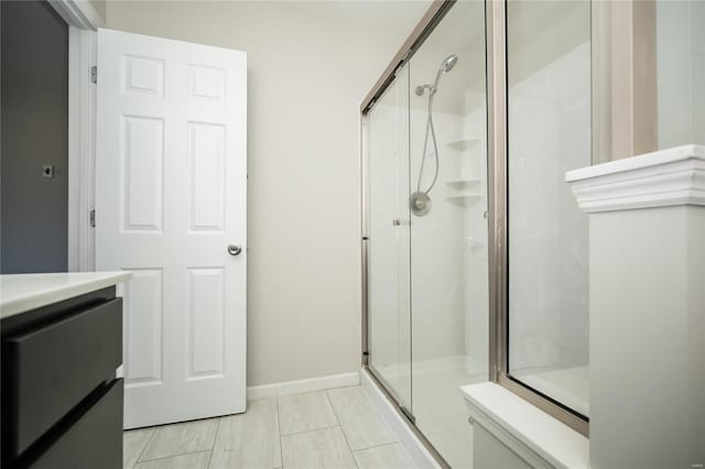 bathroom with a stall shower, baseboards, vanity, and toilet