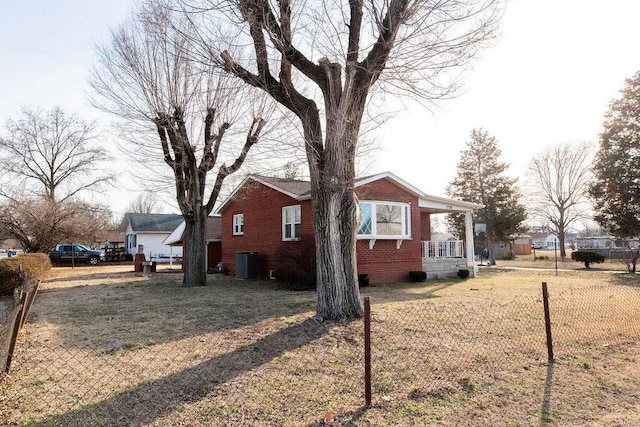 view of side of property with brick siding, fence, central AC, and a lawn