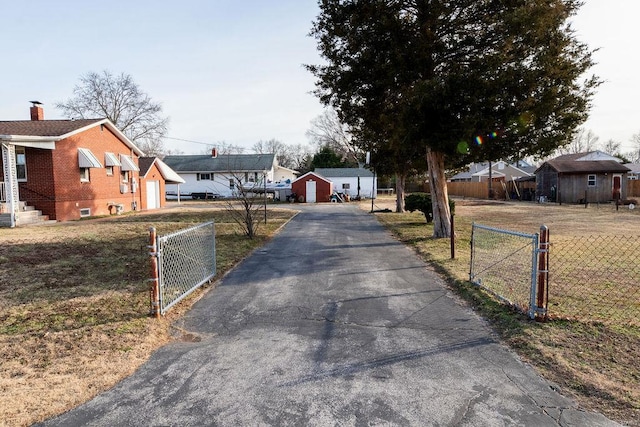 view of street featuring a gate, a gated entry, aphalt driveway, and a residential view