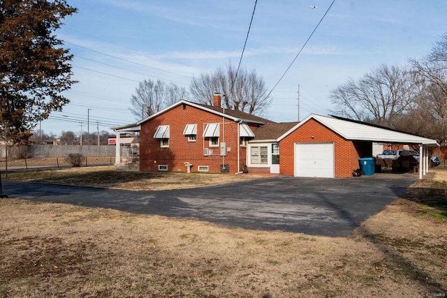 exterior space featuring driveway, a garage, a chimney, fence, and brick siding