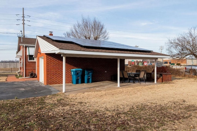 view of side of property featuring solar panels, brick siding, and a patio