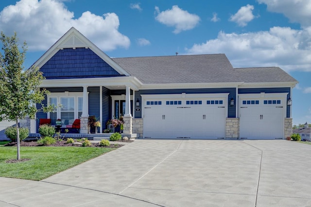 craftsman-style house featuring a garage, stone siding, a front lawn, and concrete driveway