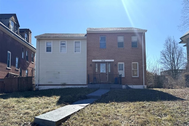 traditional-style home with a front yard, fence, and brick siding