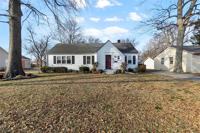 view of front facade with entry steps, a chimney, and a front yard