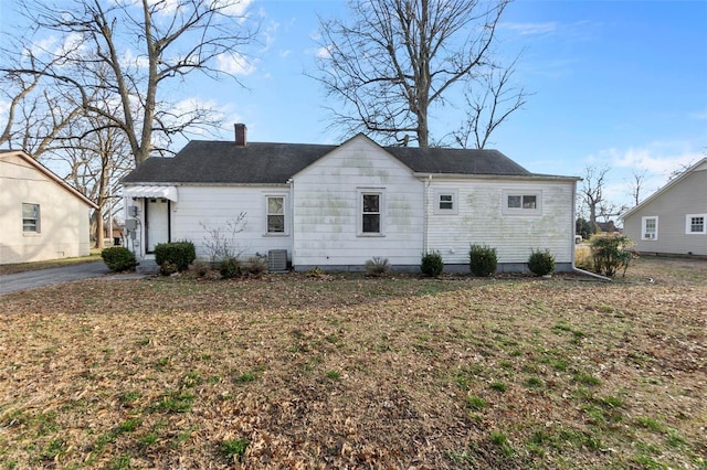 rear view of property featuring a yard, a chimney, and central air condition unit