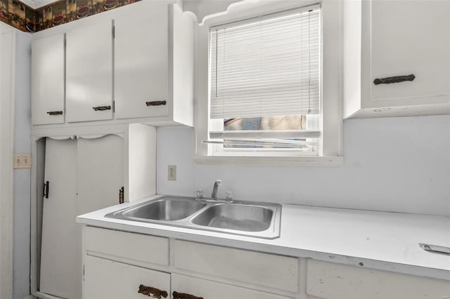 kitchen with light countertops, a sink, and white cabinetry