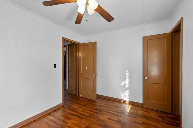 spare room featuring ceiling fan, ornamental molding, dark wood-style flooring, and baseboards