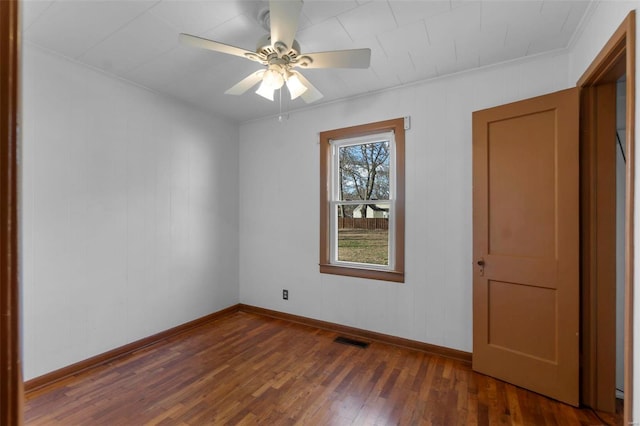 empty room featuring ceiling fan, wood-type flooring, visible vents, and baseboards