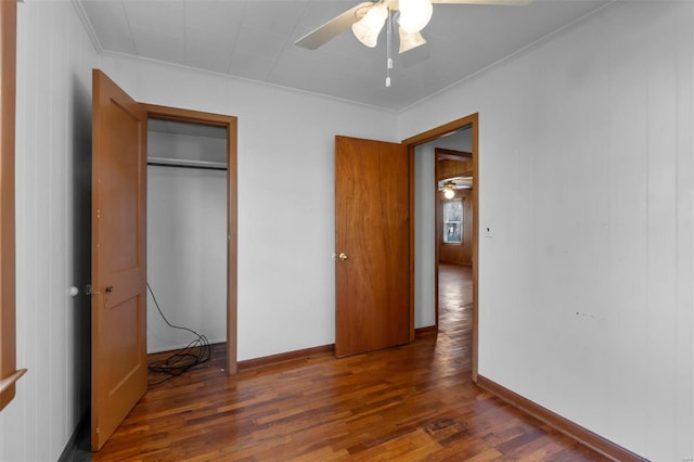 unfurnished bedroom featuring a closet, ornamental molding, ceiling fan, wood finished floors, and baseboards