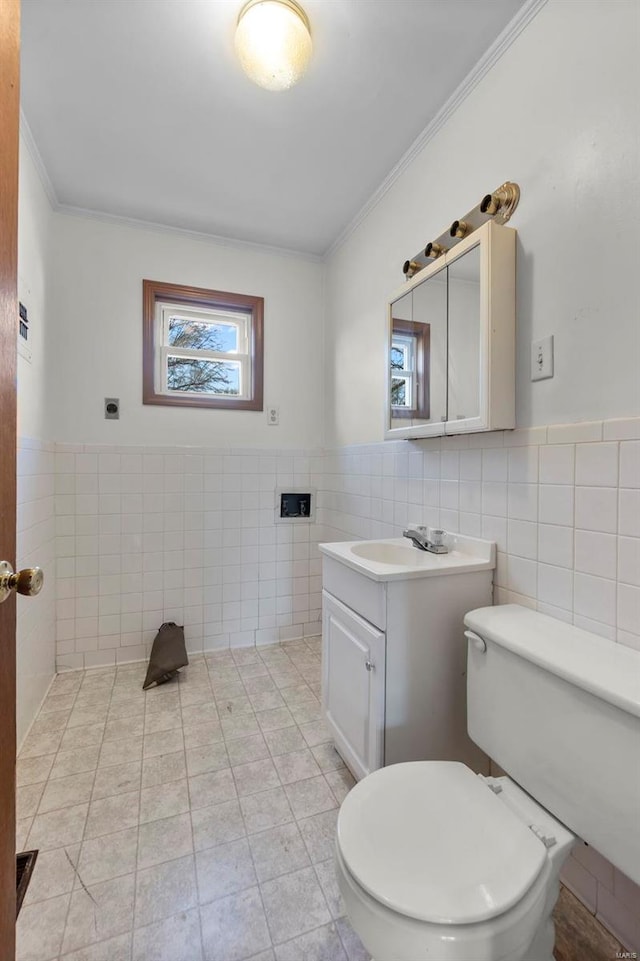 half bathroom with toilet, crown molding, tile walls, and vanity