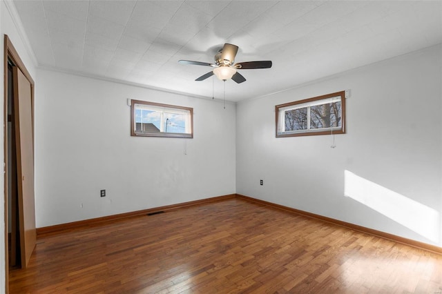 unfurnished bedroom with crown molding, visible vents, ceiling fan, baseboards, and hardwood / wood-style flooring