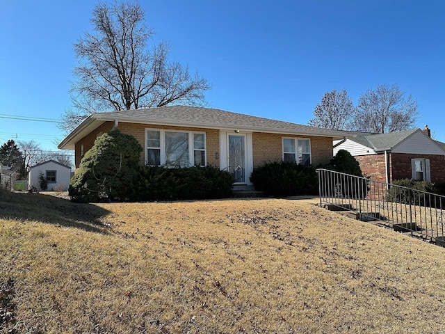 view of front of house featuring brick siding, roof with shingles, and fence