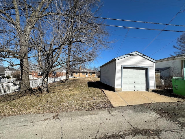 detached garage featuring fence and driveway