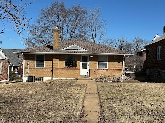 view of front facade featuring a front yard, brick siding, a chimney, and entry steps