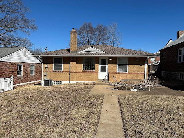 back of property featuring brick siding, central AC unit, a chimney, and a patio