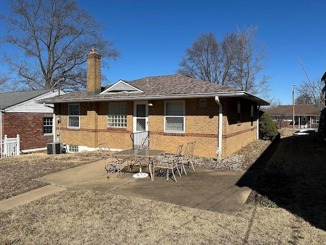 back of property with a patio, brick siding, central AC, and a chimney