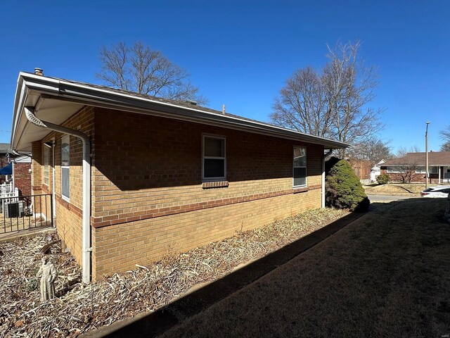 view of side of home with cooling unit and brick siding