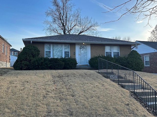 view of front of property featuring brick siding, a front yard, and a shingled roof