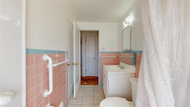 full bathroom featuring toilet, tile walls, wainscoting, tile patterned flooring, and vanity