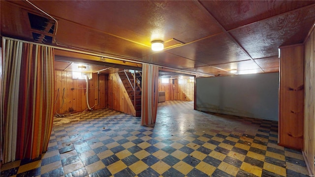 finished basement featuring tile patterned floors, stairway, and wooden walls