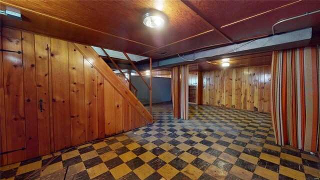 finished below grade area with tile patterned floors, stairway, and wood walls