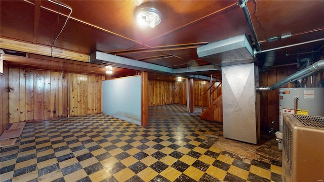 finished basement featuring tile patterned floors, wooden walls, gas water heater, and stairs