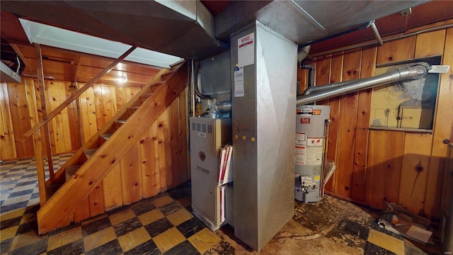 finished basement with stairs, tile patterned floors, water heater, and wood walls