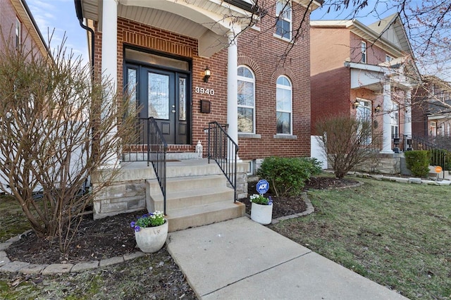 view of exterior entry featuring a yard and brick siding