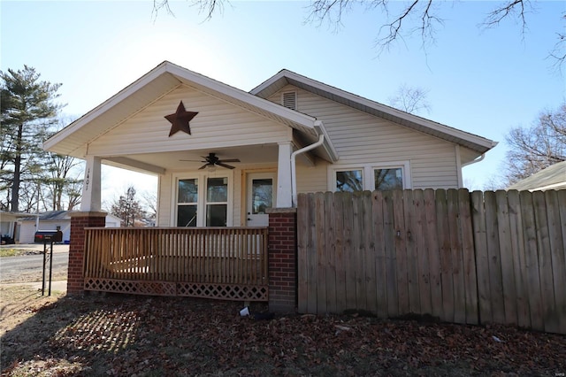 bungalow-style home featuring ceiling fan and fence