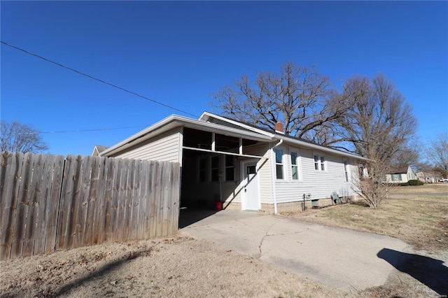 rear view of property with driveway, fence, and a chimney