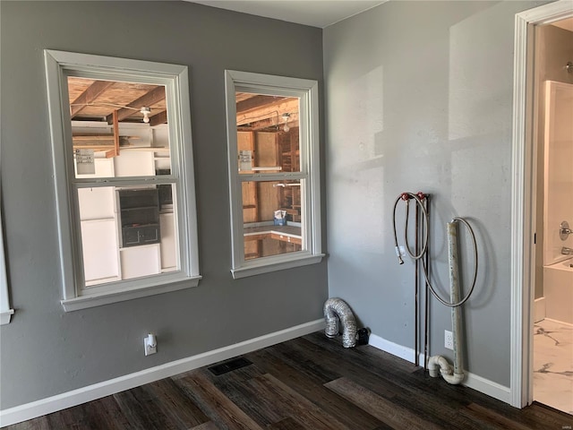 interior space with hookup for a washing machine, laundry area, visible vents, baseboards, and dark wood finished floors