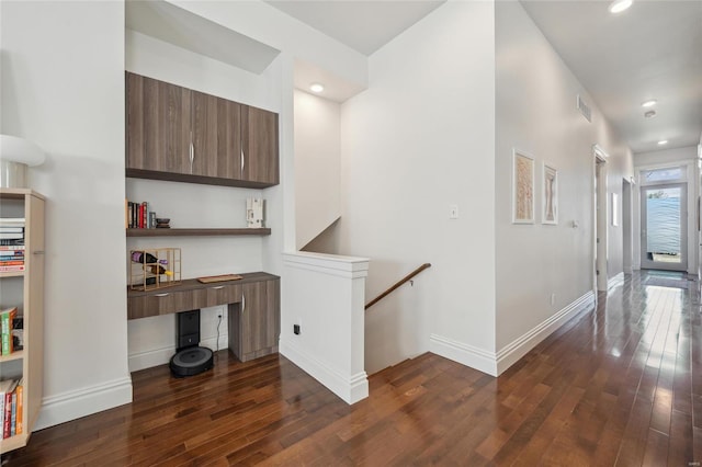 corridor featuring visible vents, baseboards, dark wood-style flooring, and an upstairs landing