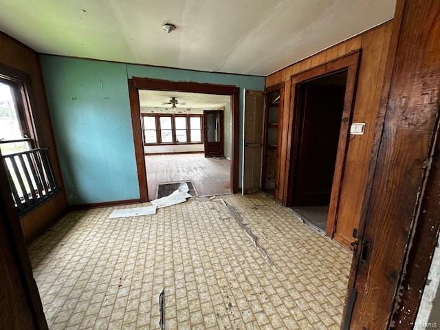 hall featuring wood walls and baseboards