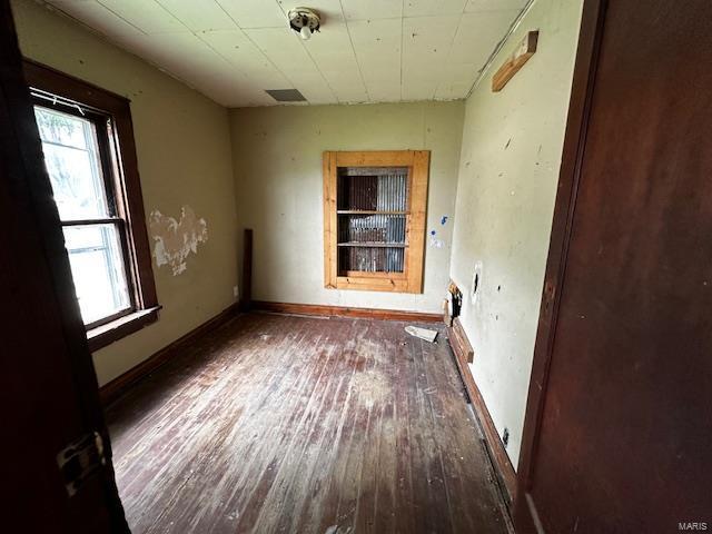 spare room featuring wood-type flooring, visible vents, and baseboards