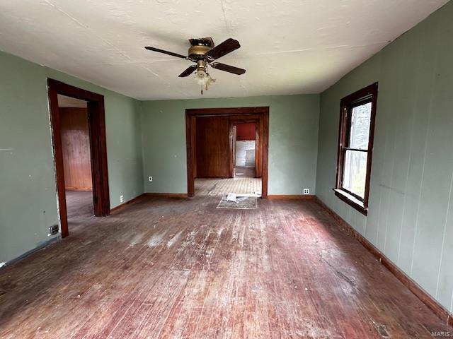 interior space with a ceiling fan, baseboards, and hardwood / wood-style flooring