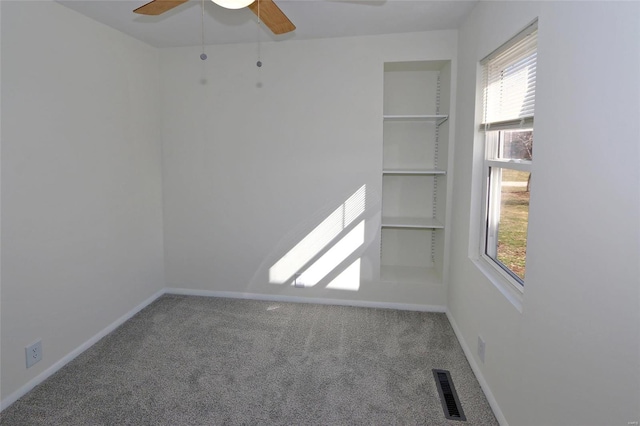 unfurnished room with baseboards, visible vents, ceiling fan, carpet floors, and built in shelves