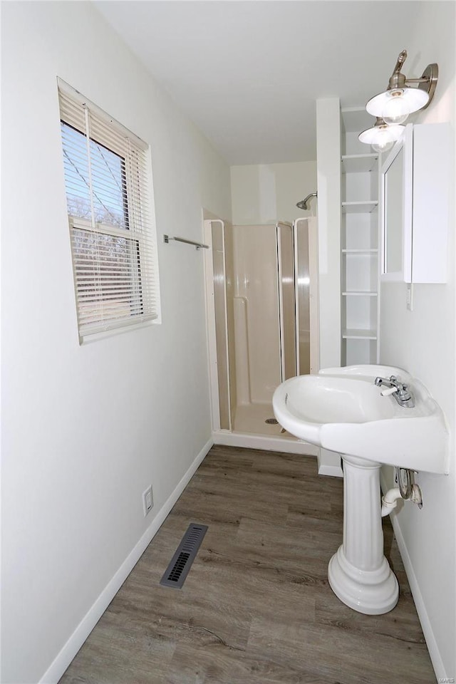 bathroom with a stall shower, baseboards, visible vents, and wood finished floors