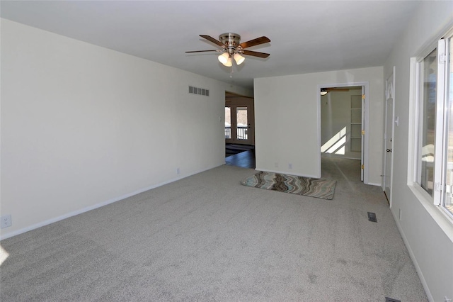 carpeted empty room featuring ceiling fan, visible vents, and baseboards