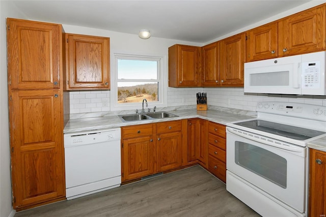 kitchen with white appliances, a sink, and brown cabinets