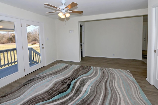 empty room with ceiling fan, baseboards, and wood finished floors