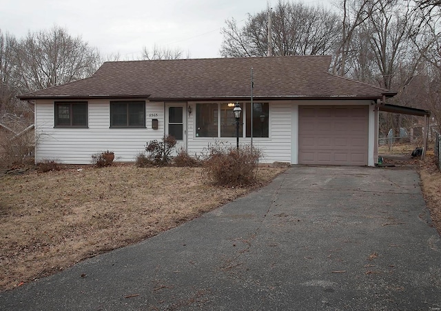 single story home with a garage, driveway, and roof with shingles