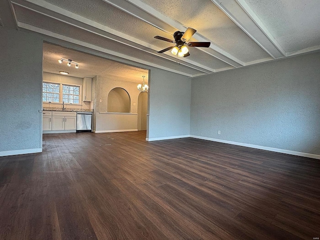 unfurnished living room with dark wood-type flooring, a sink, beamed ceiling, baseboards, and ceiling fan with notable chandelier