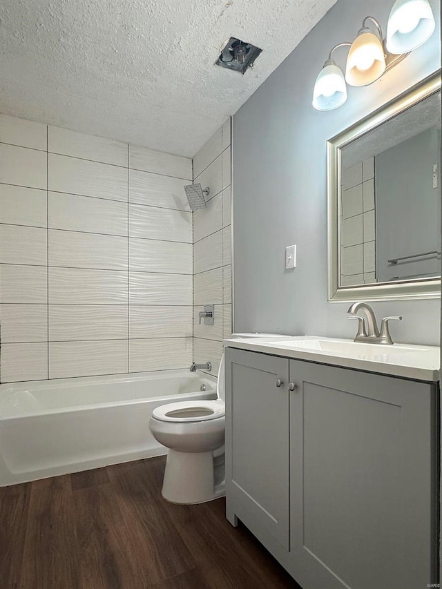 full bath featuring wood finished floors, toilet, vanity, shower / tub combination, and a textured ceiling