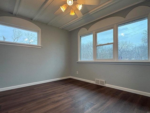 empty room featuring plenty of natural light, baseboards, visible vents, and dark wood-type flooring